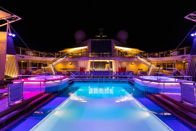 Foto piscina de luxo para navios de cruzeiro à noite no convés superior com vistas panorâmicas e áreas de entretenimento