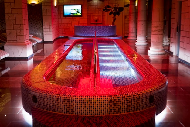 Piscina de mergulho de luxo no centro do spa de design de coluna Uma piscina de spa cheia em um salão com pilares de sauna delicada Aquazone interno projetado com iluminações de colunas de piscina em mosaico