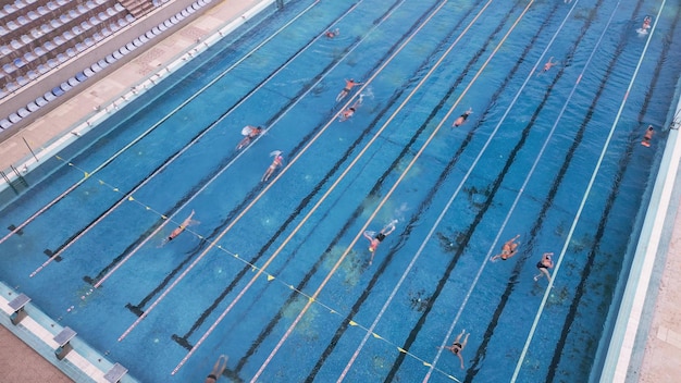 La piscina deportiva abierta brillaba bajo el sol brillante mientras la gente nadaba en sus tentadoras aguas.