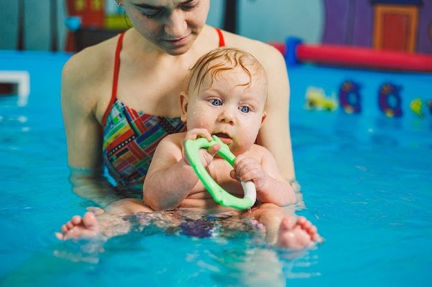 Piscina para enseñar a nadar a los recién nacidos Bebés nadando en la piscina Enseñar a un niño recién nacido a nadar en una piscina con un entrenador