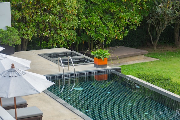 Piscina con escalera de metal con fondo de naturaleza verde