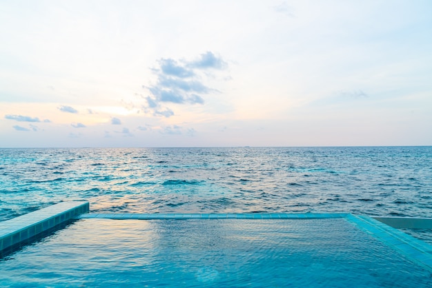 piscina exterior com mar oceano e céu pôr do sol