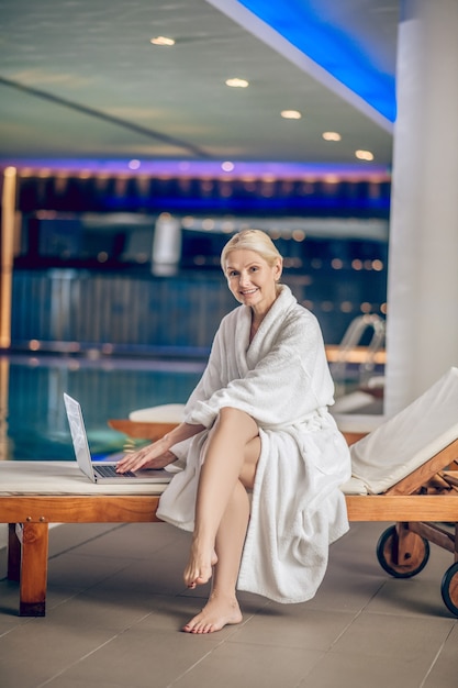 En una piscina. Pretty Woman en una túnica blanca con un portátil en una piscina