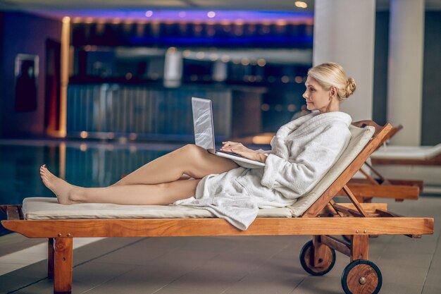 En una piscina. Pretty Woman en una túnica blanca con un portátil en una piscina