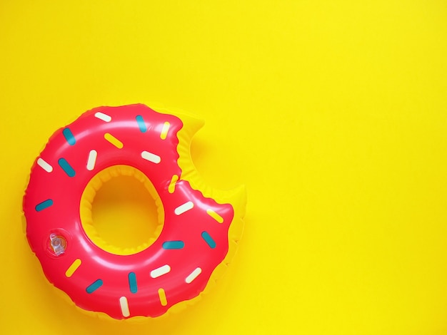 Foto piscina rosa flutuar em forma de donut na superfície amarela