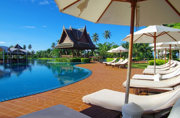 Piscina tropical con cocotero y sombrilla blanca