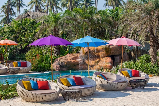 Foto piscina con tumbonas relajantes y sombrilla en jardín tropical