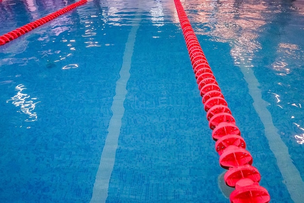 Piscina vazia com muitas pistasUma piscina esportiva vazia com um caminho de divisão vermelho Água azulFoco seletivoPista e pistas de uma piscina de competição