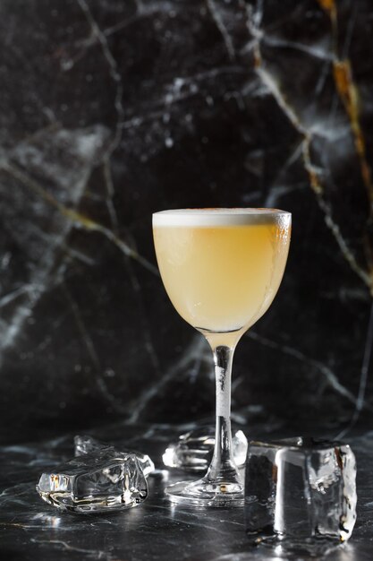 Pisco sour cocktail whisky con jarabe de azúcar de clara de huevo de lima en vidrio sobre fondo oscuro y borroso Espacio para texto