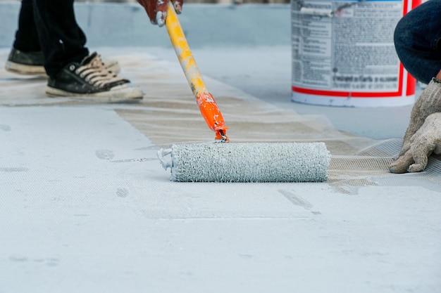 Piso cinza pintado à mão com rolos de pintura para rede de reforço à prova d'água