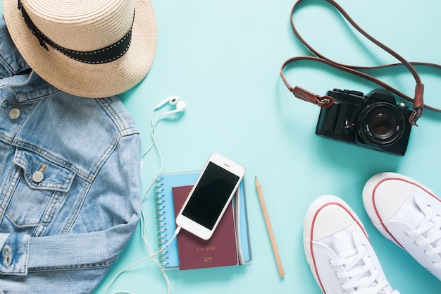 Foto piso de artigos de viagem com dispositivo móvel, passaporte e câmera em fundo de cor pastel