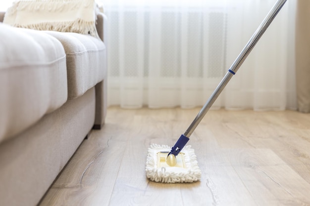 Piso de limpieza con trapeador blanco cerca del sofá