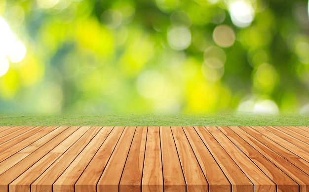 Piso de madera con árboles borrosos del fondo del parque natural y temporada de verano