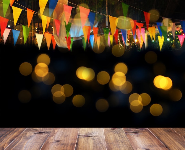 Foto piso de madera y coloridas banderas sobre bokeh para fondo de decoración de fiesta nocturna