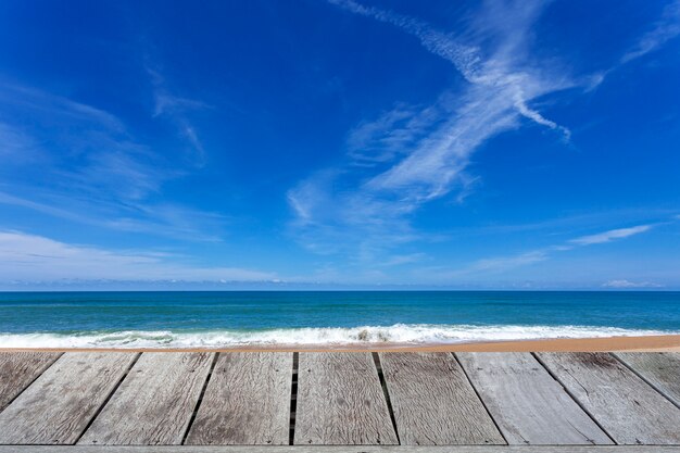 Piso de madera con hermoso cielo azul sobre el paisaje tropical de playa de arena