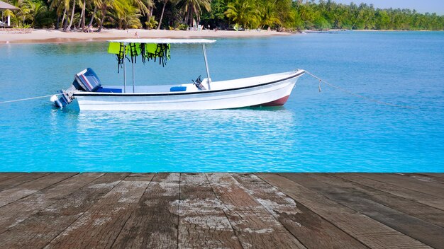 Piso de madera con mar de un bote pequeño para viajar y fondo de paisaje natural de la isla