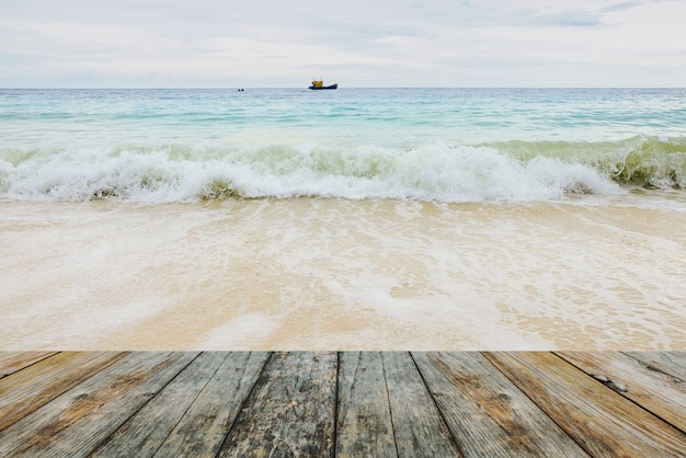 Foto piso de madera sobre olas rompiendo en la playa.