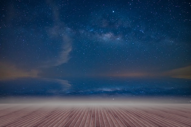 Foto piso de madera y telón de fondo del cielo de la vía láctea en la noche