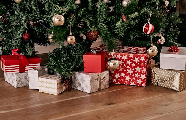 Piso de Navidad y caja de regalo por árbol para la celebración de la temporada festiva y la fiesta Sorpresa de Navidad y gratitud con presente en el suelo de la sala de estar sin nadie para el anuncio y las vacaciones