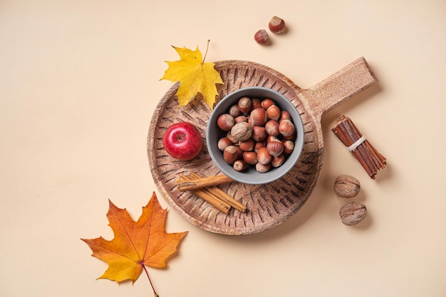 Piso de otoño con hojas de arce de colores brillantes con manzana y nueces en una tabla de cortar de madera sobre fondo naranja Vista superior y espacio de copia