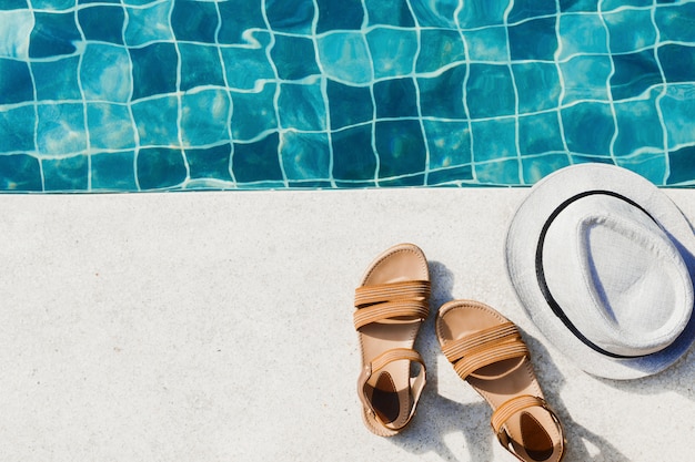 Piso de vacaciones con sandalias de mujer y gorro frente a la piscina