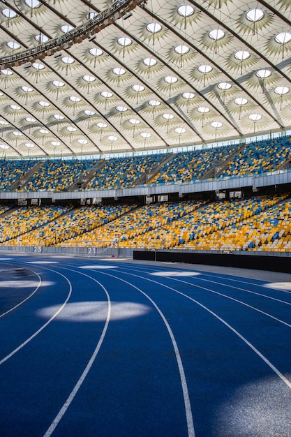 Pista de corrida azul vazia no estádio olímpico contra o fundo de arquibancadas vazias