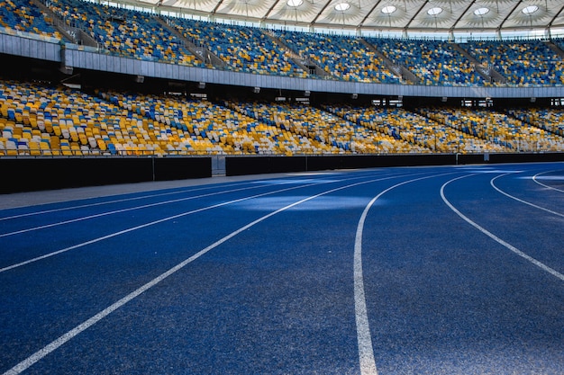 Pista de corrida azul vazia no estádio olímpico contra o fundo de arquibancadas vazias