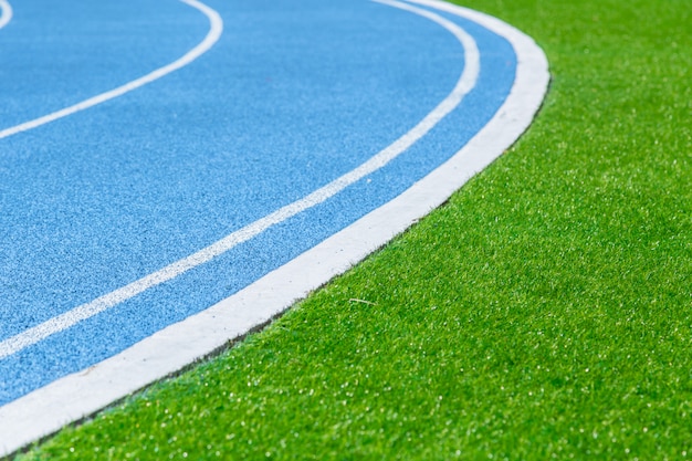 Pista de corrida com grama verde no estádio do esporte para o fundo do exercício