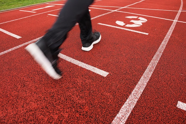 Pista de corrida vermelha no estádio com duas pernas em corrida