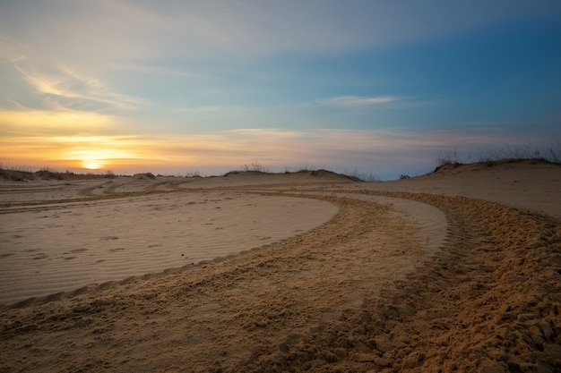 Pista de motocross e auto esporte com fundo do céu do sol. Marcas de rodas na areia