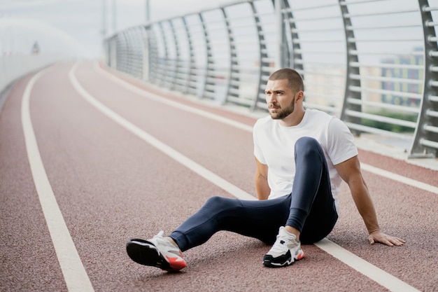 Pista esportiva para correr um homem sentado depois de um treino pensando em morena de saúde