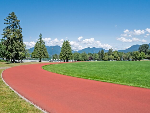 Pista de jogging roja del estadio recreativo en un día soleado y brillante