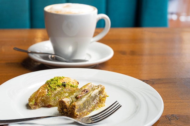 Pistache baklava, uma sobremesa tradicional turca em um prato branco, com uma xícara de café