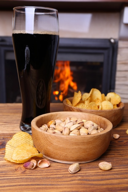 Foto pistacho, patatas fritas y cerveza sobre un fondo de una chimenea encendida