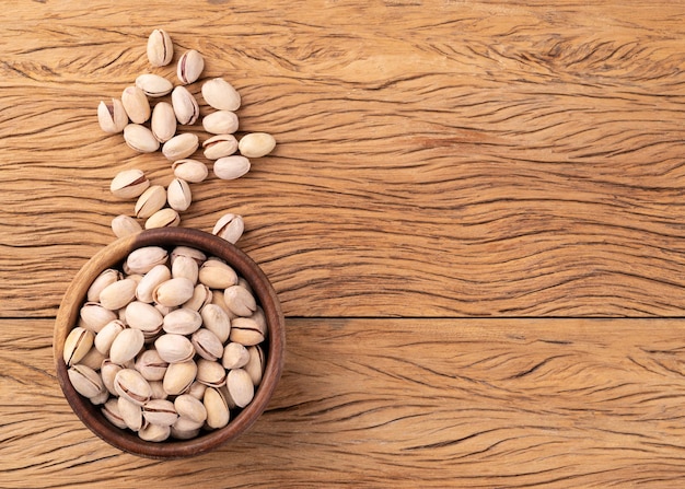 Foto pistachos asados salados en un cuenco sobre una mesa de madera con espacio para copiar