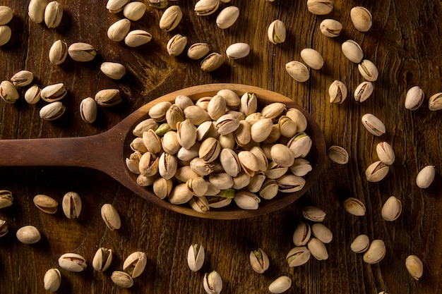 Pistachos en cuchara de madera sobre fondo de madera