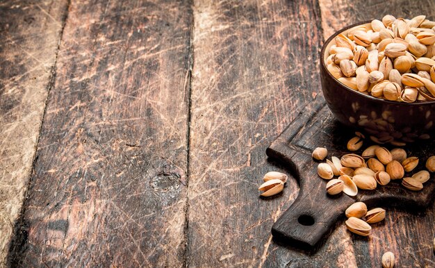 Pistachos en un cuenco sobre el tablero. Sobre fondo de madera.