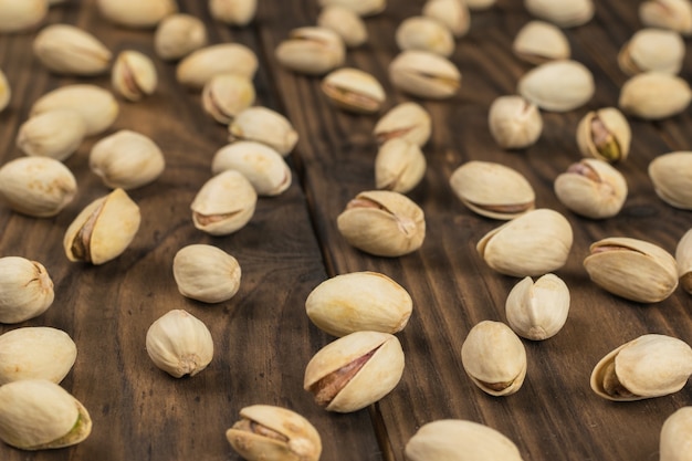 Pistachos esparcidos sobre mesa de madera. Fuente natural de proteínas y carbohidratos.