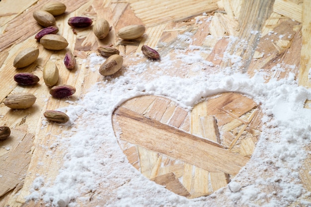 Pistachos y forma de corazón en mesa de madera