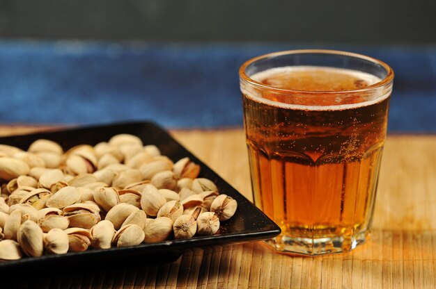 Pistachos en un plato y un vaso de cerveza