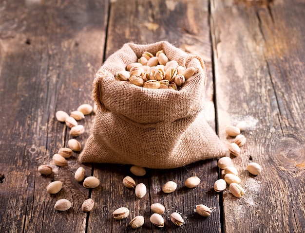 Pistachos en un saco de mesa de madera