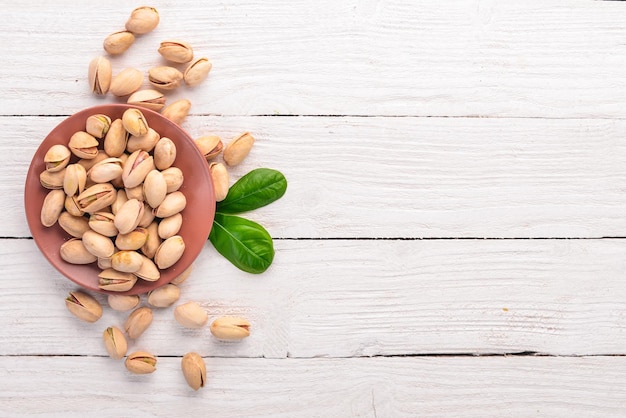 Pistachos sobre un fondo blanco de madera Aperitivos saludables Vista superior Espacio libre para texto