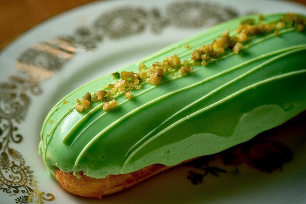 Pistazien-Eclair mit grüner Glasur in einem weißen Teller auf Holzuntergrund