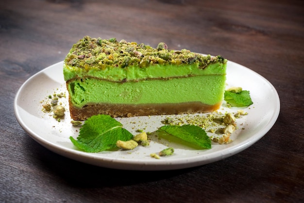 Pistazien-Käsekuchen-Portion mit Matcha-Geschmack und Minze Ein hellgrünes Stück Dessert auf einem Teller