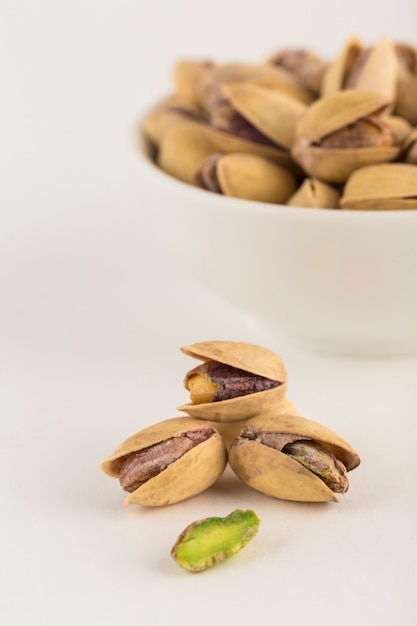 Foto pistazien nahaufnahme auf hellem hintergrund und in einer weißen schüssel. ein naturprodukt für die ernährung. seitenansicht mit einem kopienraum. vertikale ausrichtung.