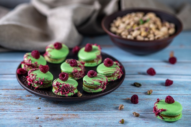 Pistazienmacarons auf Holzuntergrund mit Himbeeren