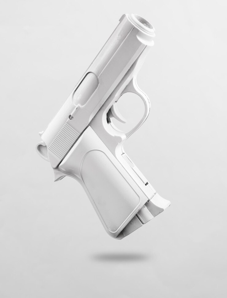 Pistola blanca levitando sobre un fondo gris con una sombra