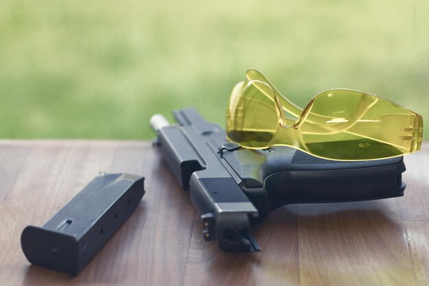 Pistola con gafas de seguridad sobre un fondo de madera.