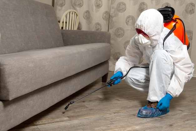 Pistola rociadora con primer plano de pesticidas Un exterminador en ropa de trabajo rocía pesticidas de una botella de spray Lucha contra insectos en apartamentos y casas Desinsectación de locales