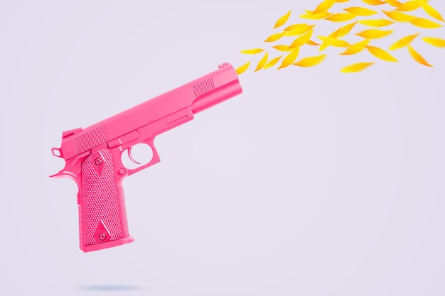 Foto pistola rosa atira flores de girassol em um fundo cinza claro revólver rosa